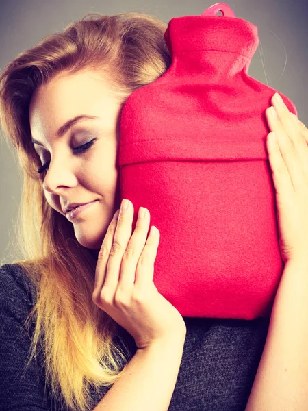 Woman hugs hot water bottle in red fleece cover — Stock Photo, Image