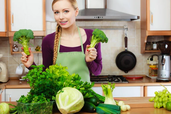 Femme dans la cuisine avec des légumes verts brocoli à la main — Photo