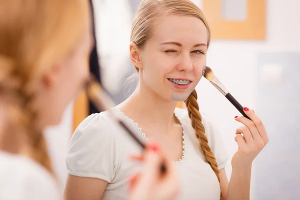 Mujer joven feliz aplicando máscara de barro en la cara — Foto de Stock