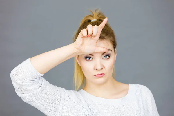 Mujer mostrando gesto perdedor con L en la frente —  Fotos de Stock