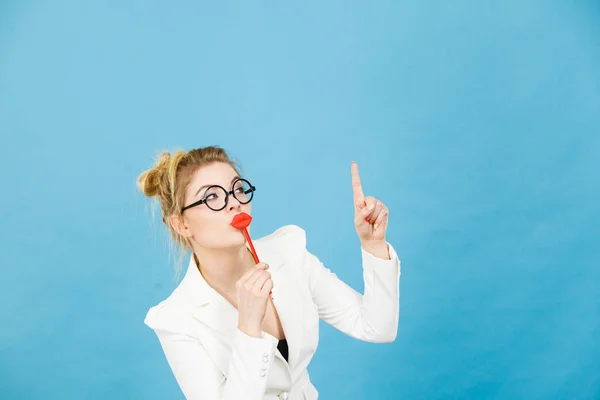 Woman holds fake lips on stick pointing at copy space — Stock Photo, Image