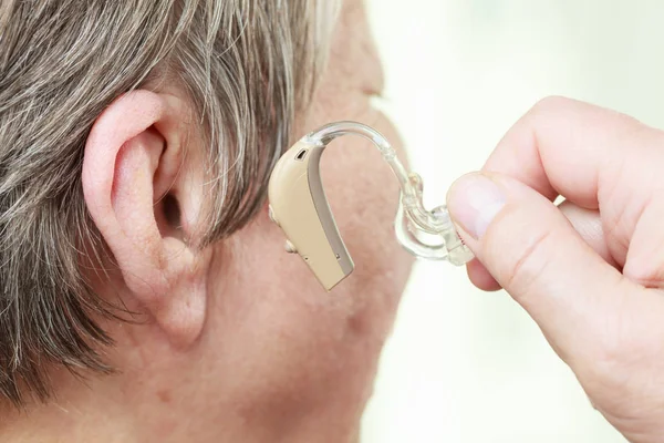 Closeup senior woman using hearing aid