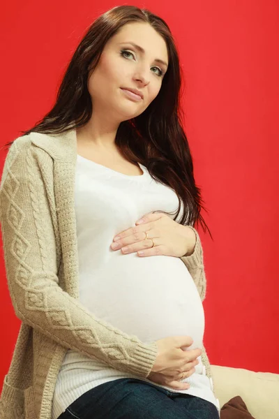 Sitting pregnant woman showing belly — Stock Photo, Image