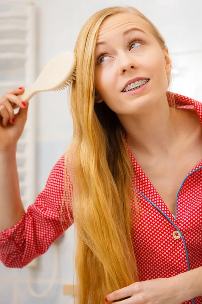 Женщина расчесывает длинные волосы в ванной — стоковое фото