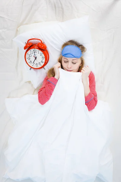 睡眼惺忪的女子穿着睡衣拿着时钟 — 图库照片