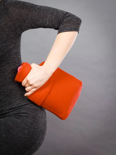 Woman holds hot water bottle in red fleece cover — Stock Photo, Image