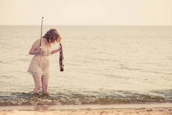 Kvinna på stranden nära havet håller fiol — Stockfoto