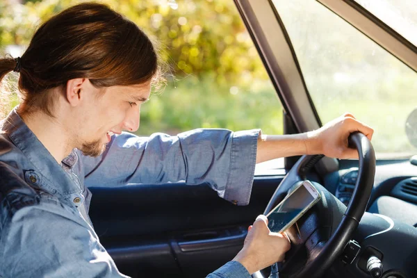 Hombre usando su teléfono mientras conduce el coche. — Foto de Stock