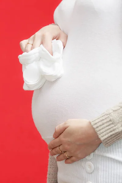 Femme enceinte tenant de petites chaussures de bébé — Photo