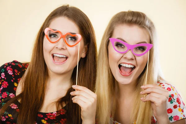 Two happy women holding fake eyeglasses on stick — Stock Photo, Image