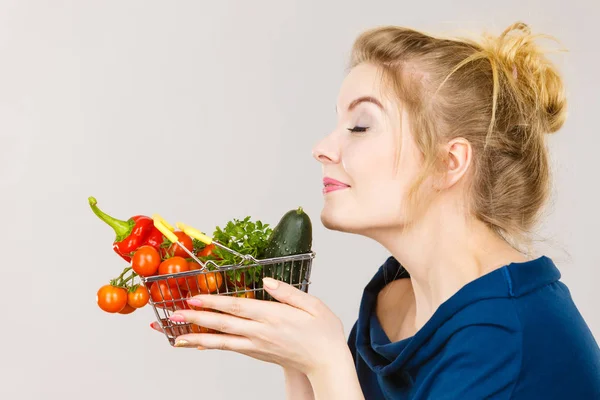 Mujer sostiene cesta de la compra con verduras, oliendo — Foto de Stock