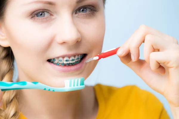 Kvinna leende rengöring tänder med hängslen — Stockfoto