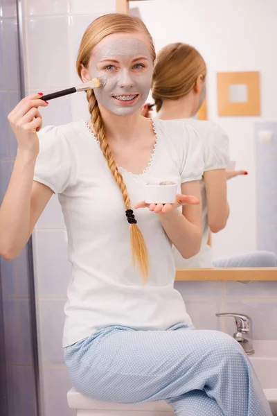 Mujer joven feliz aplicando máscara de barro en la cara — Foto de Stock