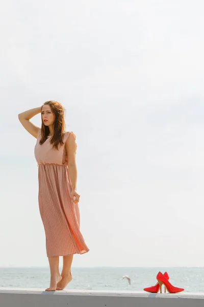 İskelede uzun hafif pembe elbise giyen kadın — Stok fotoğraf