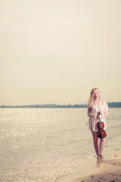 Kvinna på stranden nära havet håller fiol — Stockfoto