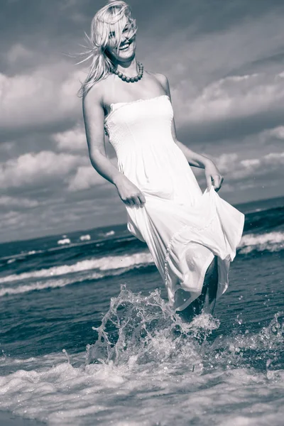 Blonde woman wearing dress walking in water — Stock Photo, Image