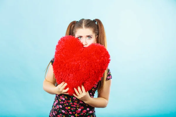 Mujer asustada sosteniendo almohada en forma de corazón — Foto de Stock