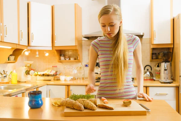 Женщина на кухне держит нож и делает здоровый сэндвич. — стоковое фото