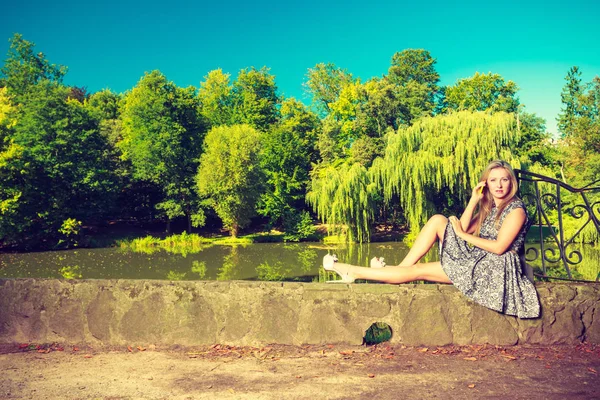 Mujer sentada en el parque, relajándose y usando el teléfono — Foto de Stock
