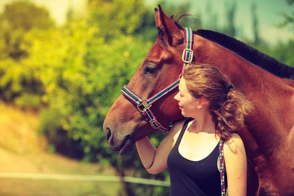 Jóquei menina petting e abraçando cavalo marrom — Fotografia de Stock