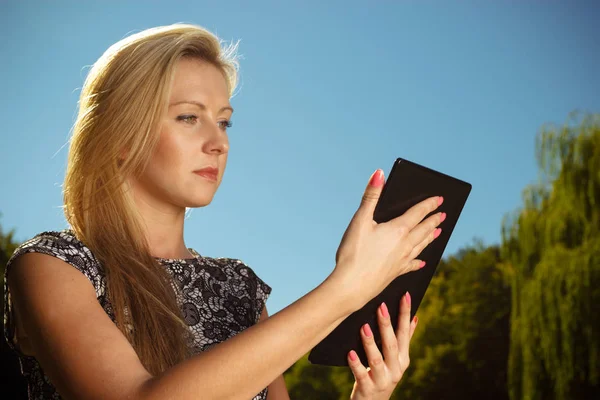 Žena sedí v parku, relaxační a používání tabletu — Stock fotografie