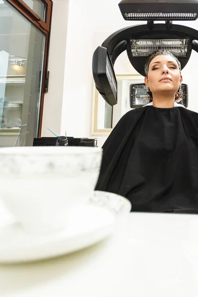 Femme dans le salon de coiffure, sèche-cheveux sous la machine — Photo