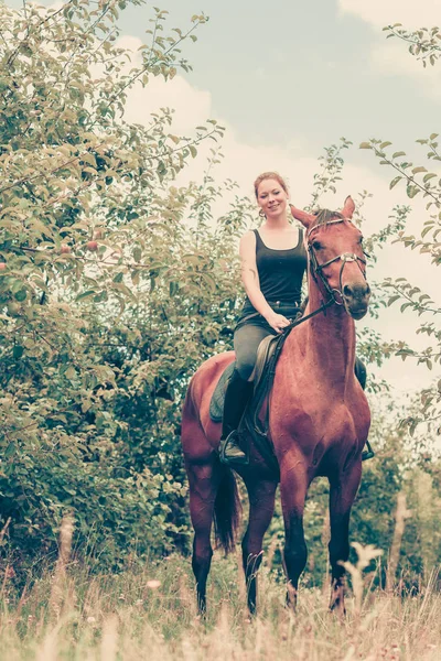 Młoda kobieta siedzi na koniu — Zdjęcie stockowe