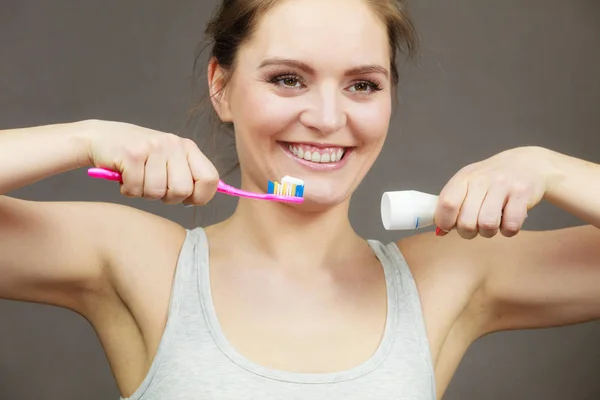 Donna che tiene lo spazzolino e ci mette sopra del dentifricio — Foto Stock