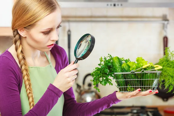 Жінка дивиться через збільшувач в кошику з овочами — стокове фото