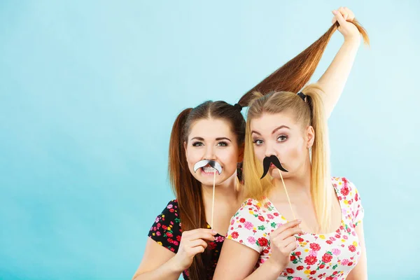 Twee gelukkige vrouwen houden van valse snor op stick — Stockfoto