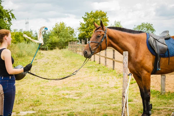 Fantino giovane donna ottenere cavallo pronto per la corsa — Foto Stock