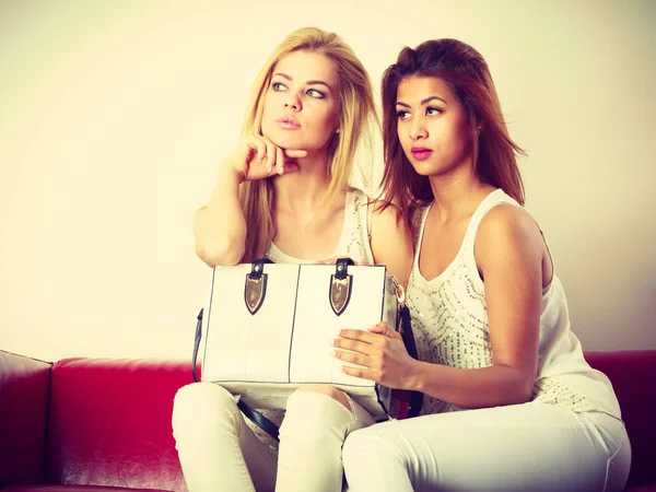 Twee vrouwen zittend op de bank presenteren tas — Stockfoto