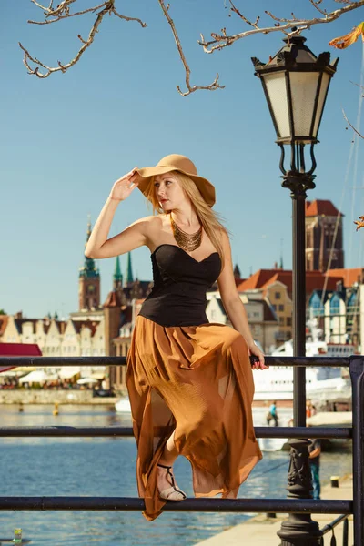 Mulher sentada vestindo grande chapéu de sol e vestido elegante — Fotografia de Stock