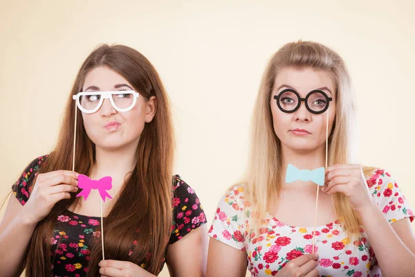 Deux femmes sérieuses tenant des accessoires de carnaval sur bâton — Photo