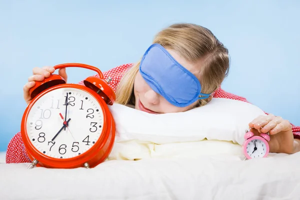 睡觉的女人穿着睡衣拿着时钟 — 图库照片