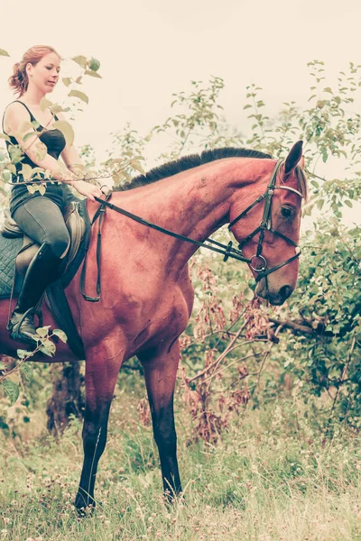 Jeune femme assise sur un cheval — Photo