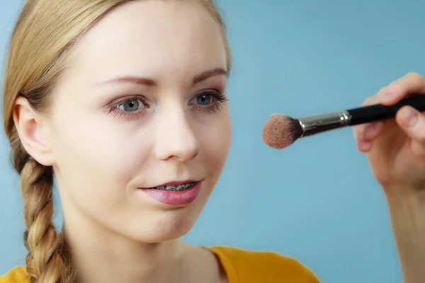 Artista de maquillaje aplicando con cepillo rouge en cheque femenino —  Fotos de Stock