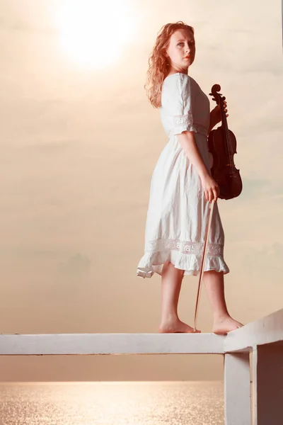 Woman on pier outside holding violin — Stock Photo, Image