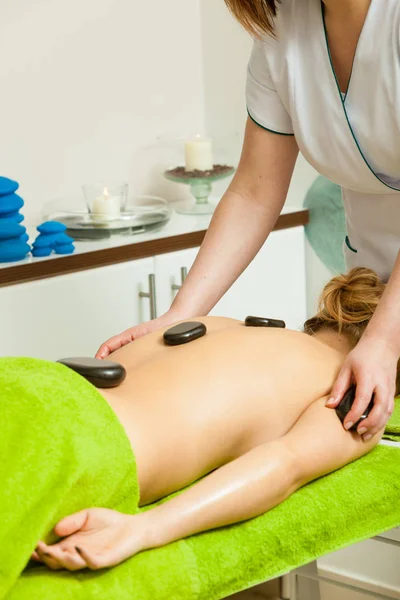 Massage mit heißen Steinen in Kosmetikerin — Stockfoto