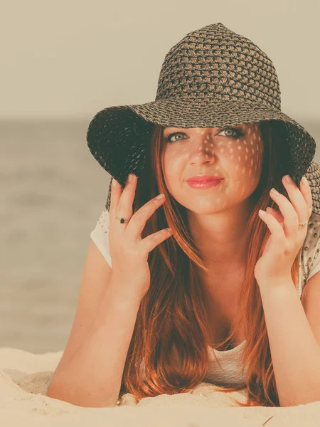 Roodharige vrouw met zon hoed liggend op het strand — Stockfoto