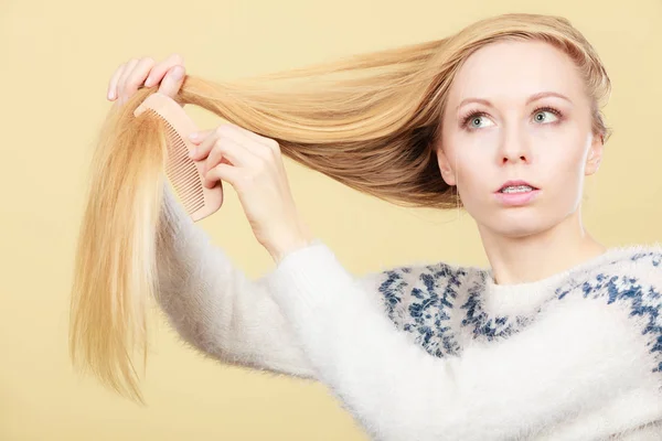 Blond tienermeisje borstelen van haar haren met kam — Stockfoto