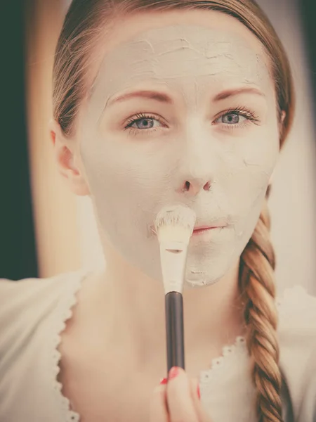 Vrouw met borstel klei modder masker toepassen op haar gezicht — Stockfoto