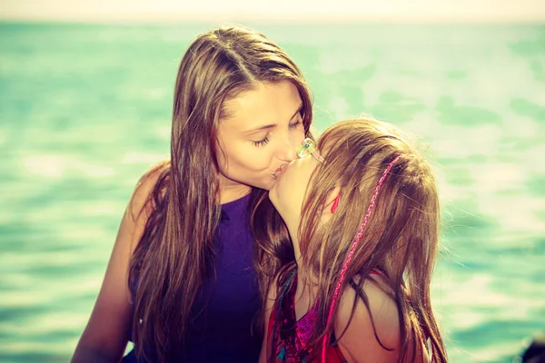 Woman and girl kissing near sea rocks — Stock Photo, Image