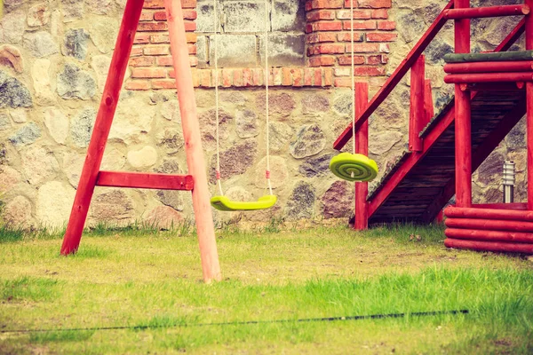 Balançar no parque infantil jardim, fundo da parede de tijolo — Fotografia de Stock