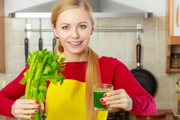 Mulher na cozinha segurando suco de smoothie vegetal — Fotografia de Stock