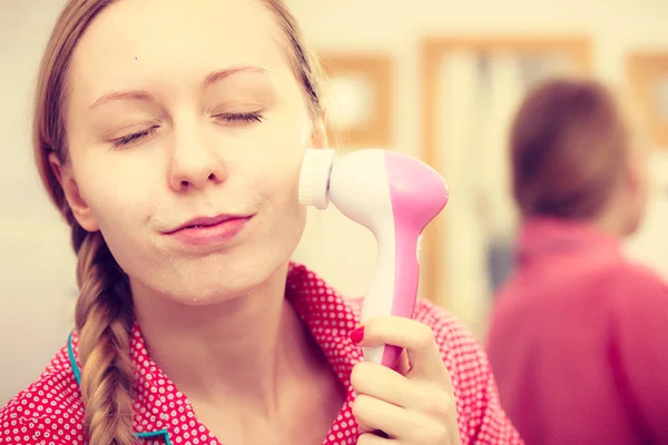 Mulher usando escova de limpeza facial no rosto — Fotografia de Stock