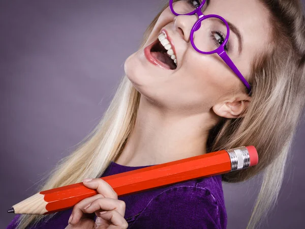 Mujer sonriente sostiene un lápiz grande en la mano — Foto de Stock