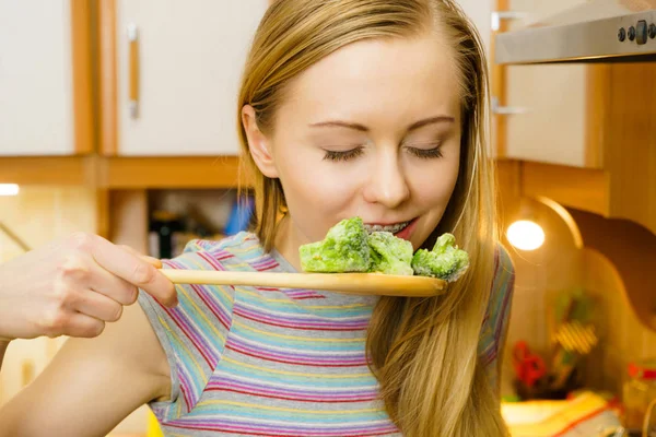 Женщина пробует жарить овощи из сковороды — стоковое фото
