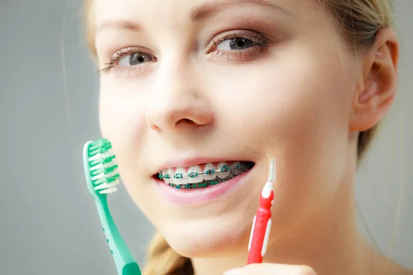 Дівчина з зубними брекетами використовує міжзубну і традиційну щітку — стокове фото