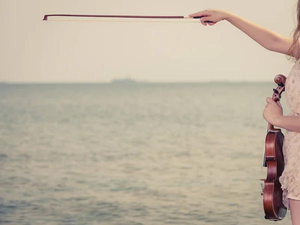 Vrouw op strand in de buurt van de zee houden viool — Stockfoto